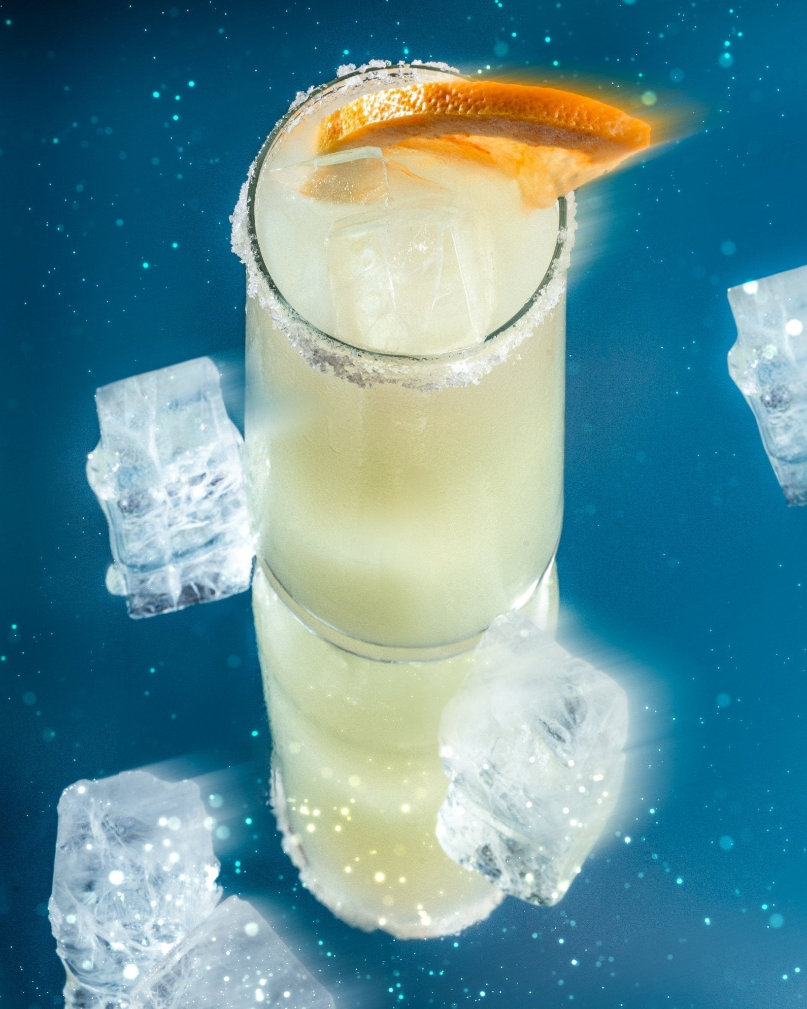 A citrusy non-alcoholic salty dog cocktail made with Cantrip Elixir,, garnished with an orange wedge and surrounded by ice cubes