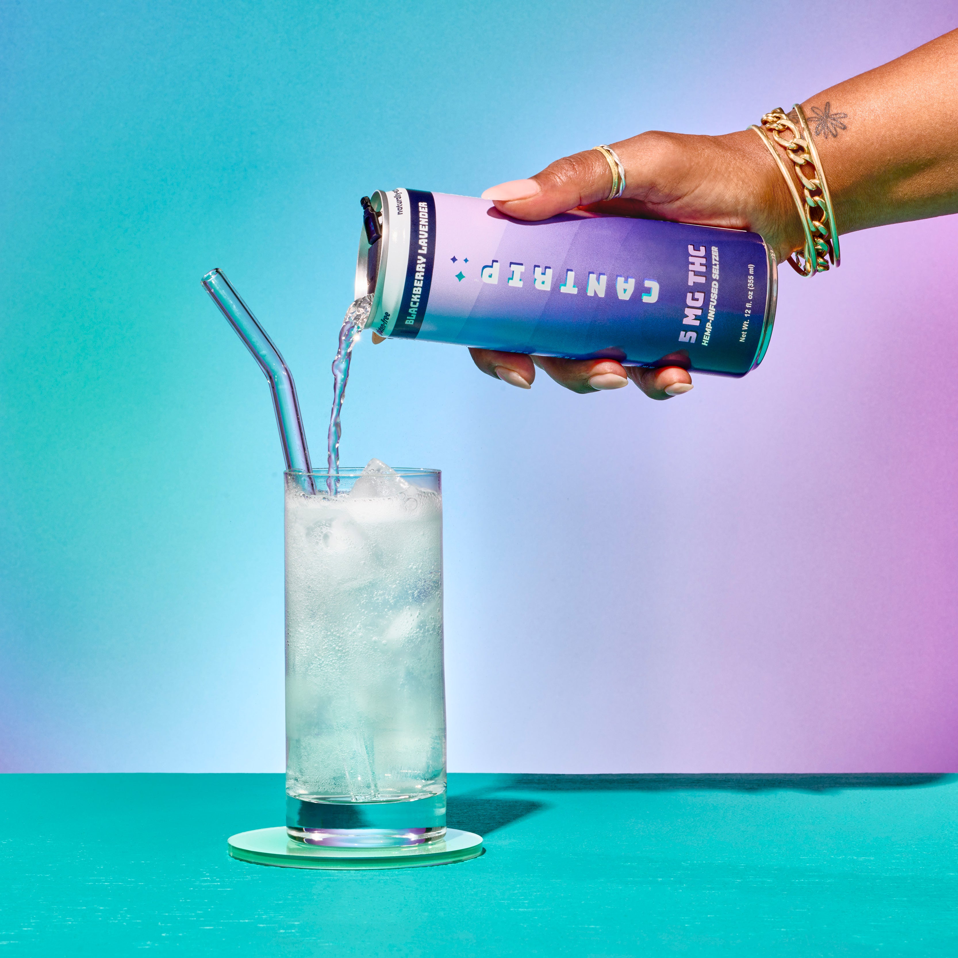 A person pouring a purple can of Cantrip Blackberry Lavender THC Seltzer (5 MG) into a glass over ice. The can reads,