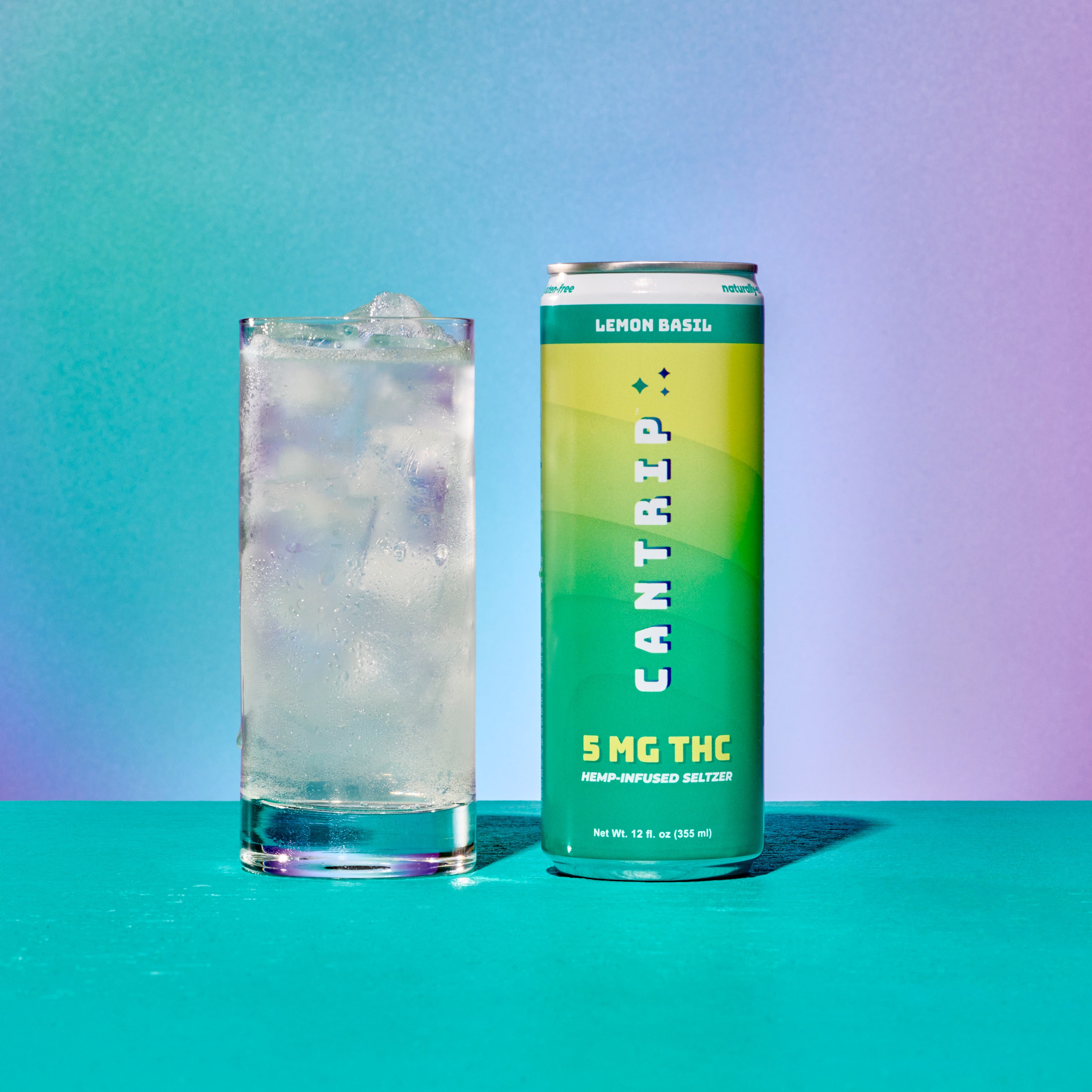 A green and yellow can of Cantrip Lemon Basil THC Seltzer next to a glass filled with seltzer and ice. The can reads,
