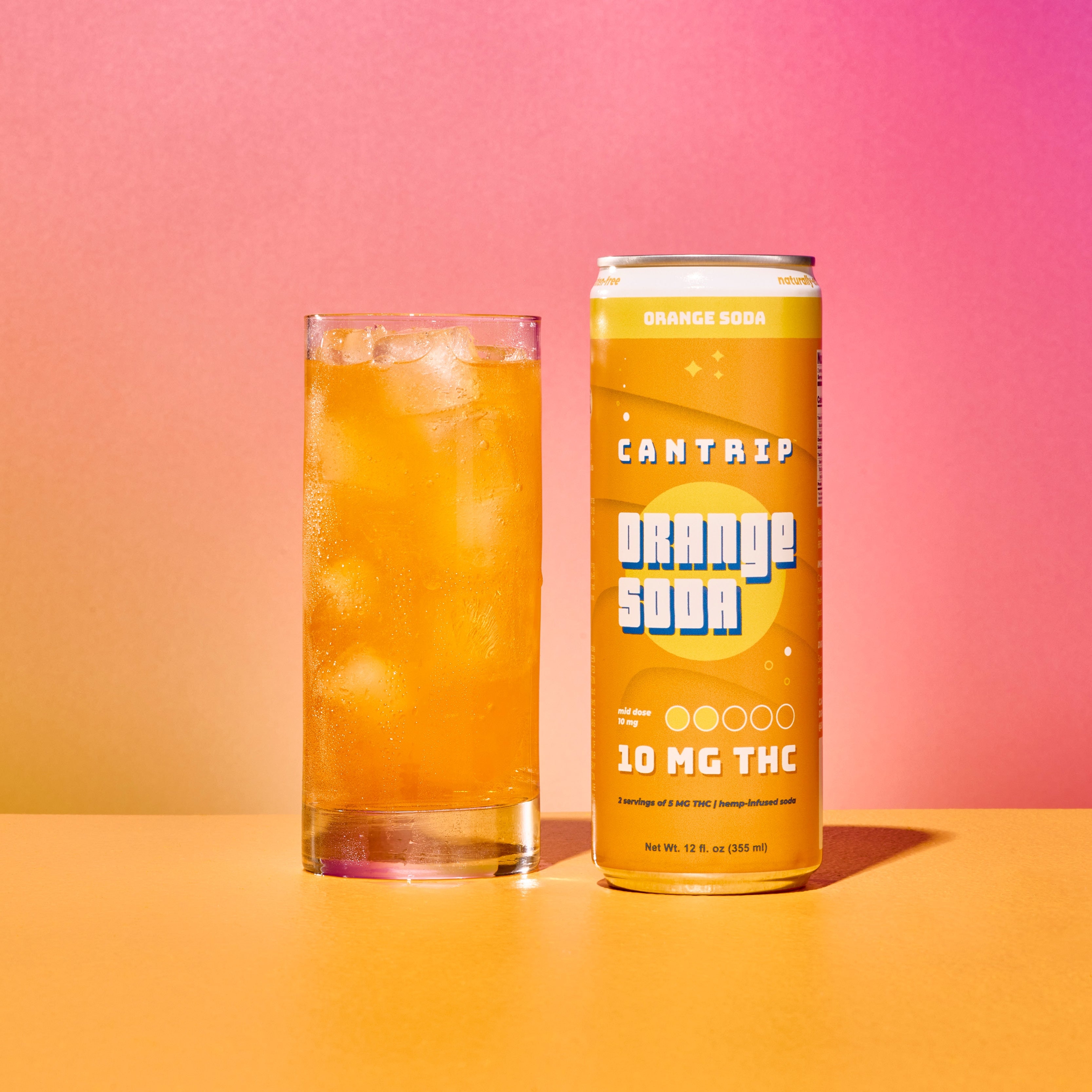 A can of Cantrip Orange Soda next to a glass filled with orange soda and ice.