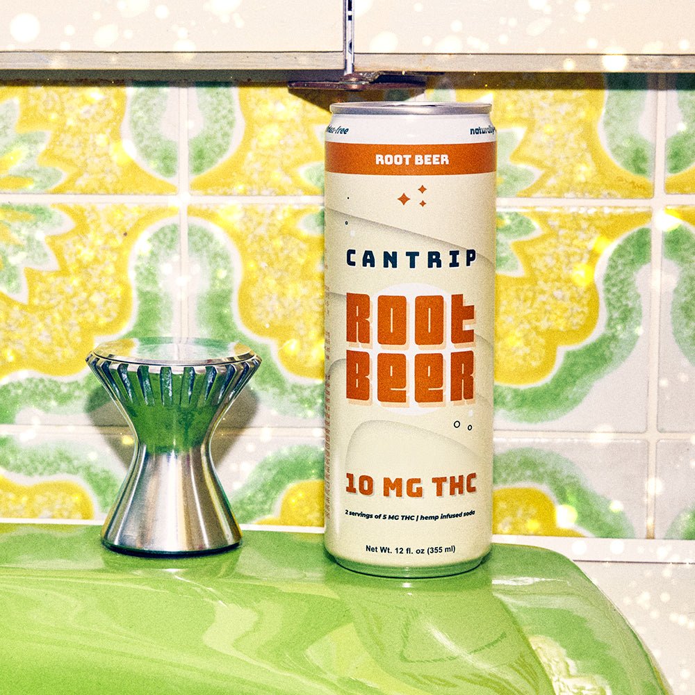 A cream-colored can of Cantrip 10 MG THC Root Beer on a counter, and set a against yellow, green and white tile.