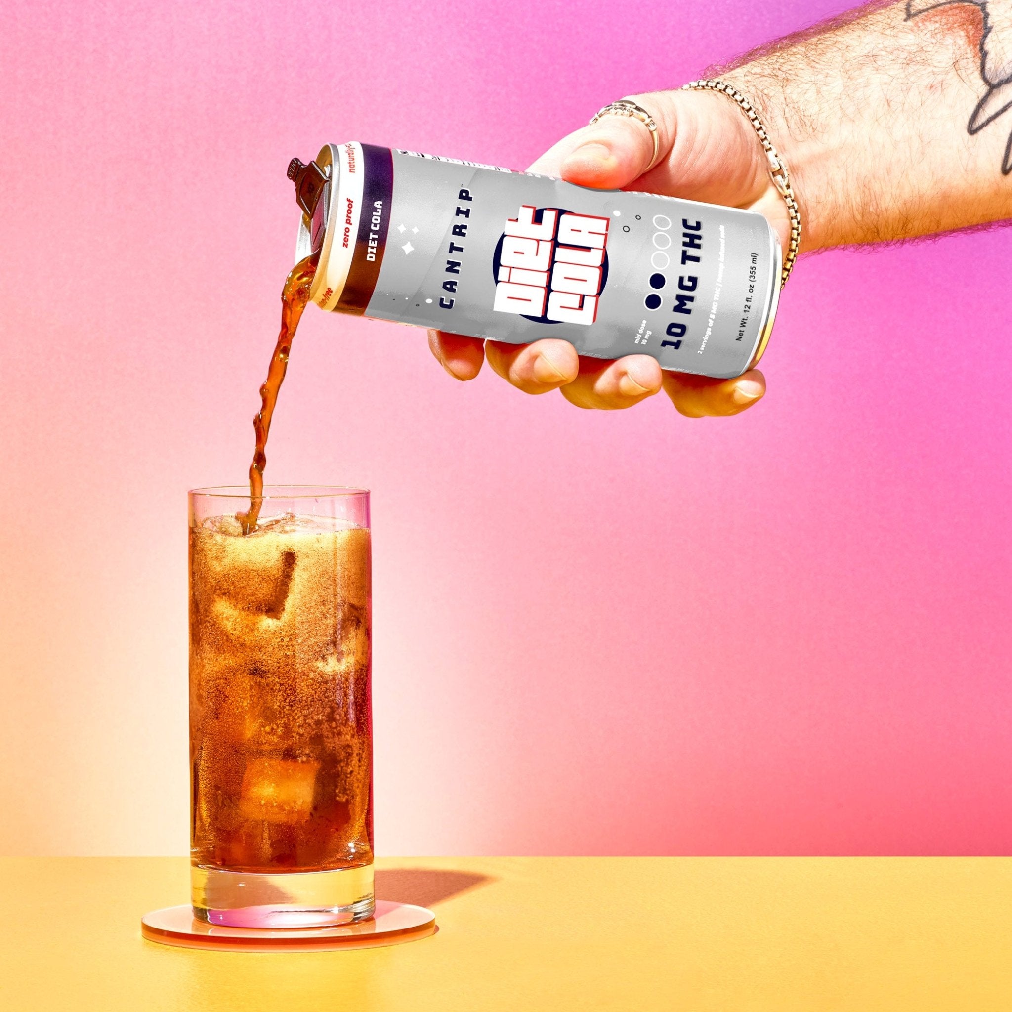 A hand reaching over to pour a refreshing Cantrip THC Diet Cola (10 MG) into a tall glass over ice.