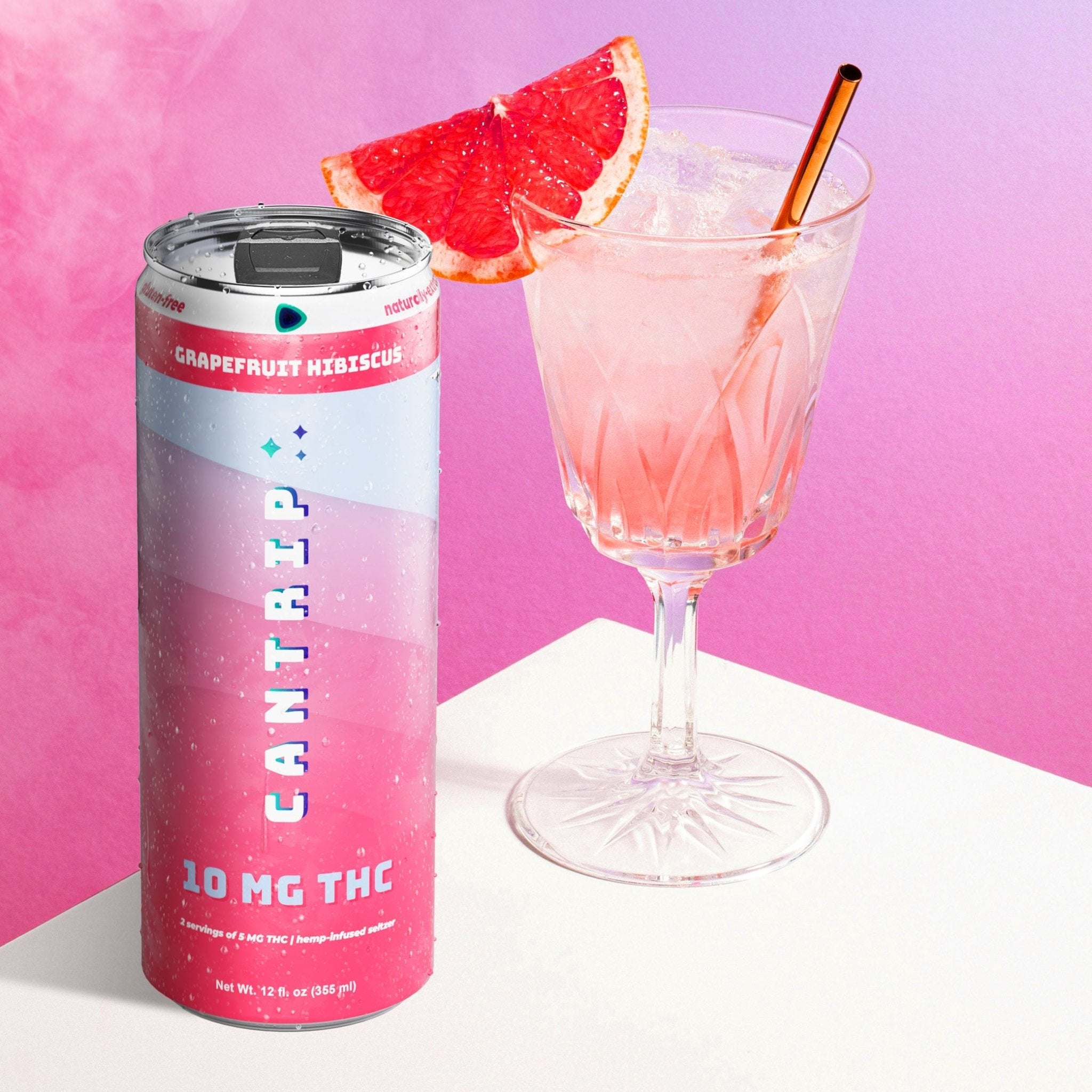 An open can of Cantrip Grapefruit Hibiscus THC seltzer. It sits next to a crystal cocktail glass with seltzer on ice, served with a grapefruit wedge.